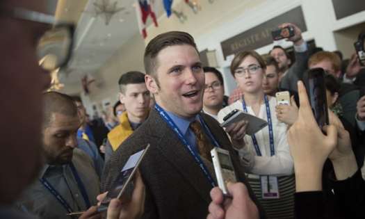 This is a photo of Richard Spencer surrounded by microphones. 